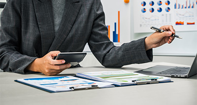 business professional analyzing data with smartphone and laptop surrounded by financial reports and charts presenting 17 key statistics