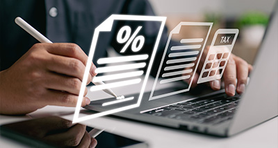 person working on a laptop with tax documents and calculations focused on managing finances for 16 tax forms