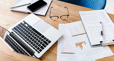 laptop on a wooden desk with documents glasses and a smartphone showing business analytics and reports related to 3 strategies 3 insights 3 data