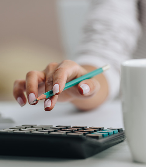 hand holding pencil over calculator with coffee cup nearby for accounting tasks and calculations in focus 2 essential items